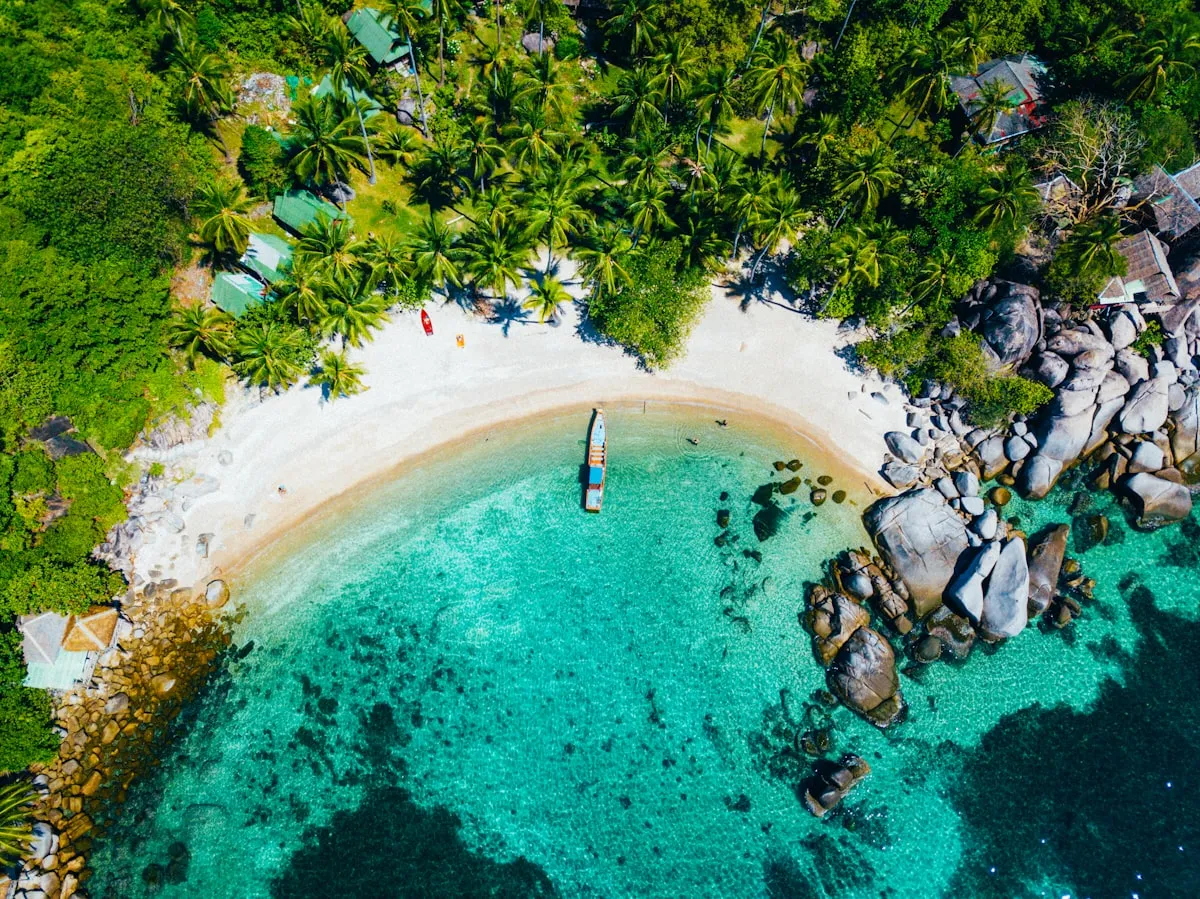Aerial view of Koh Samui coastline with turquoise water and coconut palms during dry season